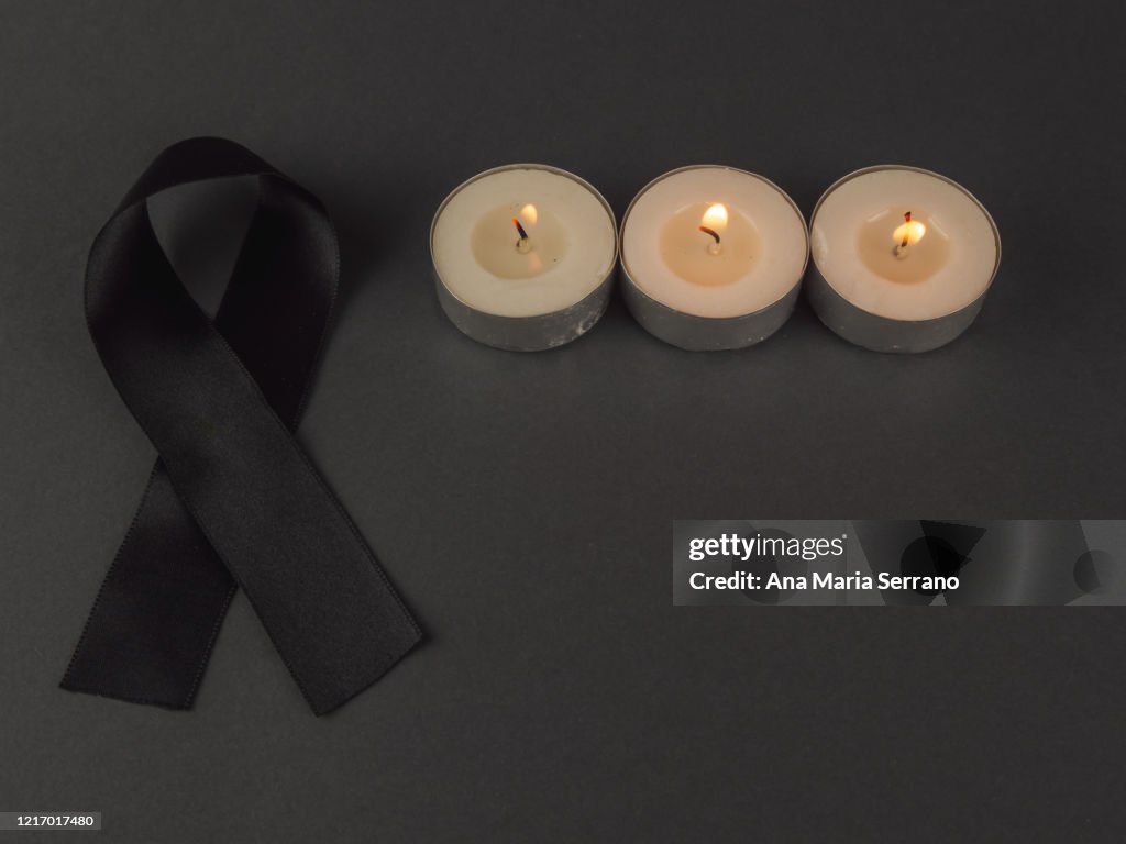 Burning candles and a black bow of black ribbon in mourning
