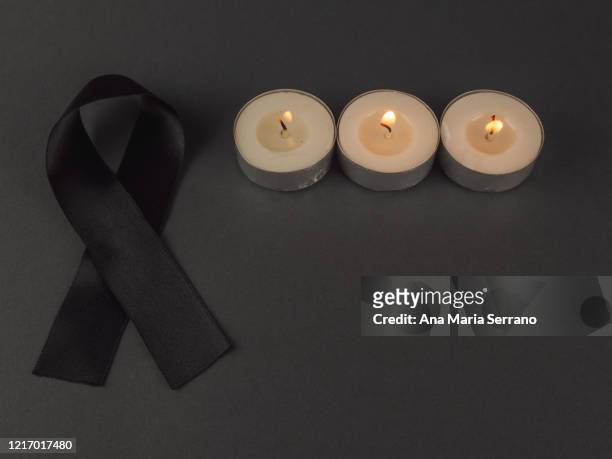 burning candles and a black bow of black ribbon in mourning - mourning candles stock pictures, royalty-free photos & images