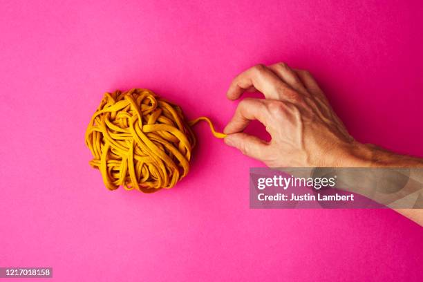 hand pulling yellow thread from a tightly wound ball - tangled yarn stock pictures, royalty-free photos & images