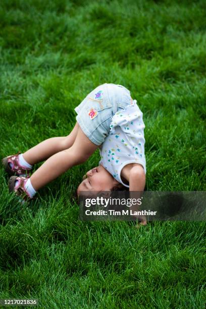 young girl doing somersaults in grass - somersault stock pictures, royalty-free photos & images