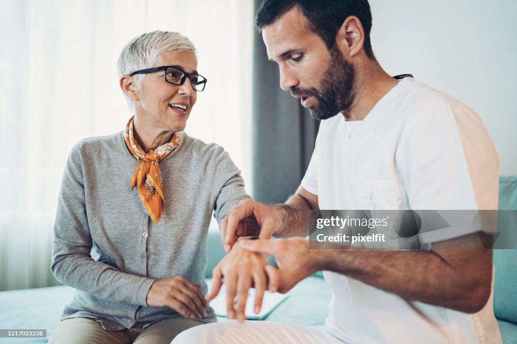 Arzt untersucht Arm und Handgelenk der Seniorin