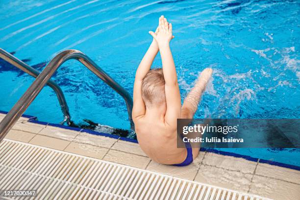 unrecognizable boy splashing water in swimming pool - hallenbad leer stock-fotos und bilder