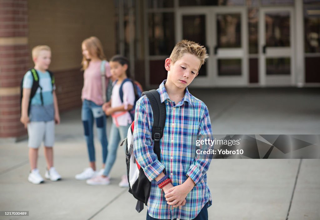 Sad boy feeling left out, teased and bullied by his classmates