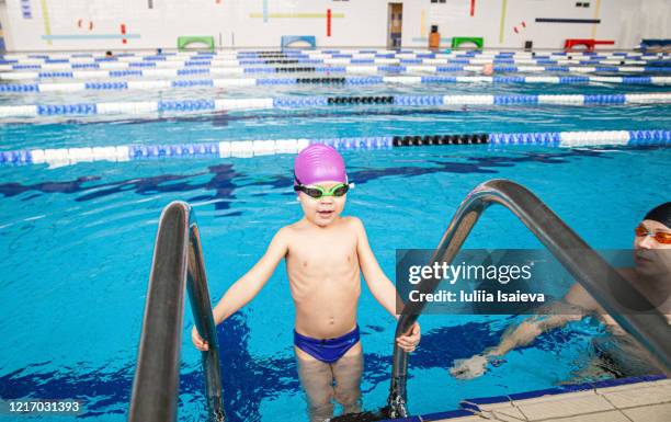 happy small preschool boy on entrance into water in lap pool with father in contemporary sports club - kids swim caps stock pictures, royalty-free photos & images