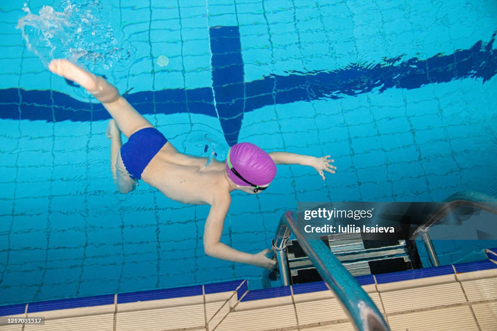 Unrecognizable boy swimming in pool