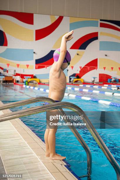 small preschool athlete performing jump exercise into water in lap pool in sports club - boy swimming pool goggle and cap stock pictures, royalty-free photos & images