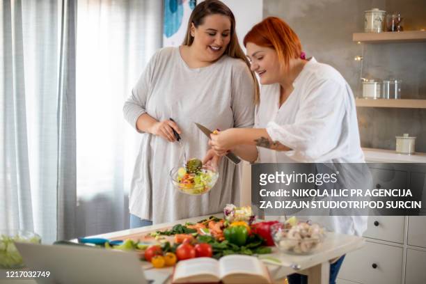 jovens sorrindo mulheres plus size preparando salada. - big fat white women - fotografias e filmes do acervo