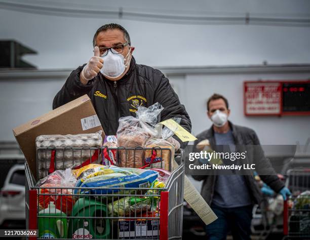 Man gives thumbs up as he and other shoppers wear masks while shopping at BJ's Wholesale Club in Freeport, New York on April 3, 2020. .