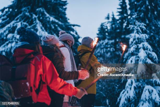 freunde wandern in der dämmerung durch den schnee - fackel stock-fotos und bilder
