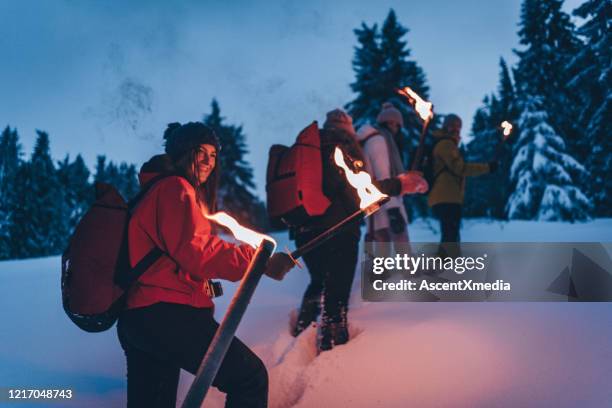 freunde wandern in der dämmerung durch den schnee - fackel stock-fotos und bilder