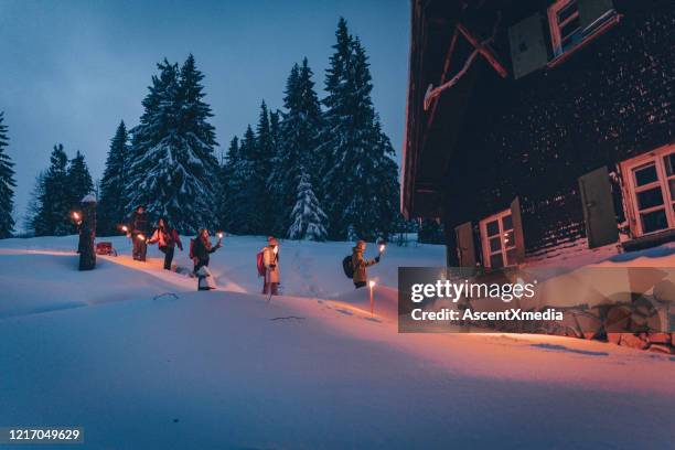 freunde wandern durch schnee zur blockhütte - fackel stock-fotos und bilder