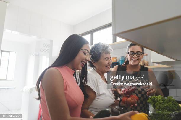 mormor, mor och dotter packar upp matvaror i köket - family teenager home life bildbanksfoton och bilder