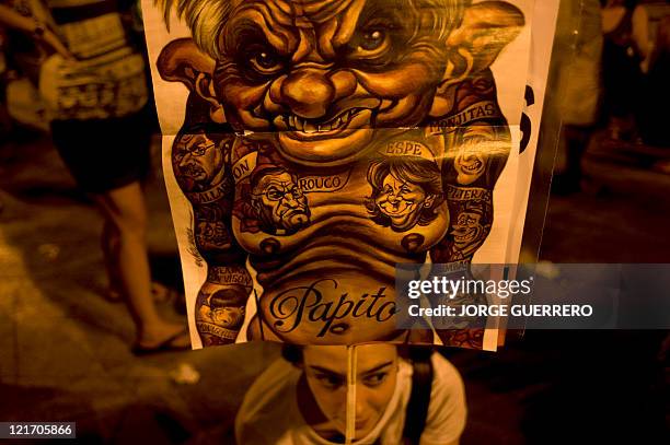 Protester holds a placard with a cartoon depecting Pope Benedict XVI during a demonstration against the public cost of the World Youth Day...