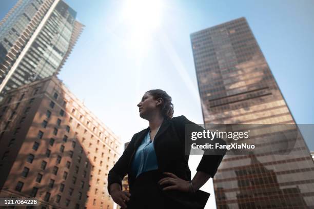 low angle view of caucasian businesswoman looking away at downtown cityscape - business hero stock pictures, royalty-free photos & images