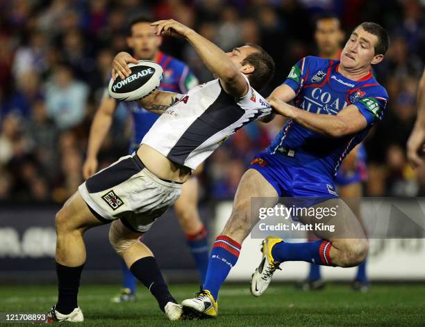 Chris Houston of the Knights tackles Scott Anderson of the Broncos around the collar during the round 24 NRL match between the Newcastle Knights and...