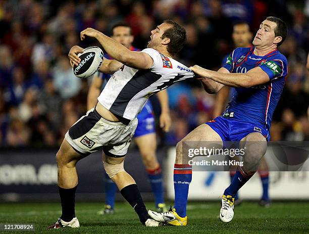 Chris Houston of the Knights tackles Scott Anderson of the Broncos around the collar during the round 24 NRL match between the Newcastle Knights and...