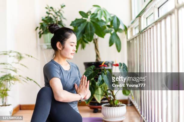 jeune femme asiatique pratiquant le yoga dans le salon - salle yoga photos et images de collection