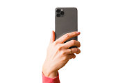 Person holding in hand mobile phone with triple lens camera