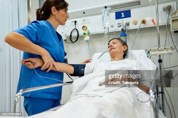 a female nurse is taking the pulse of middle aged patient. - post operation stock pictures, royalty-free photos & images