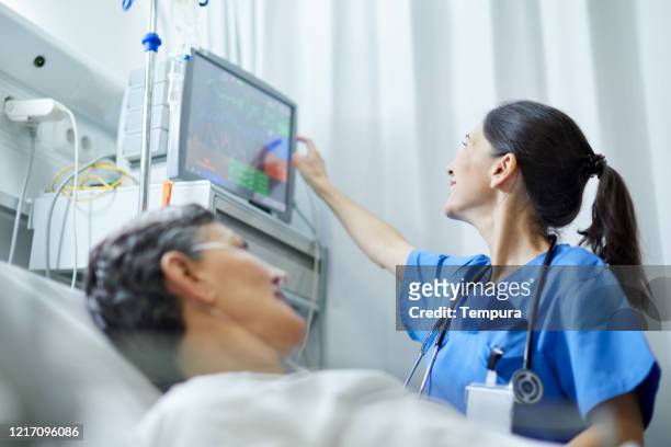 eine krankenschwester, die sich die vitalzeichen anschaut, überwacht. - icu patient stock-fotos und bilder