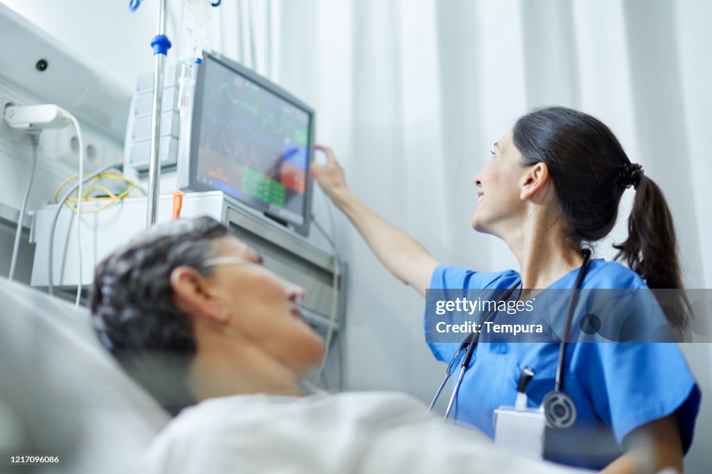 A nurse looking at the vital signs monitor.