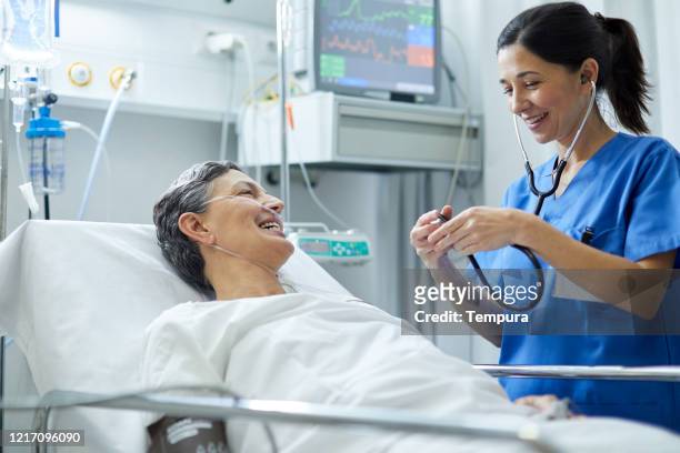 a female nurse is listening with a stethoscope the heart bit of a patient. - post operation stock pictures, royalty-free photos & images
