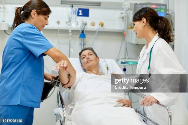 a female nurse is taking the pulse of patient in the post operative area. - post operation stock pictures, royalty-free photos & images