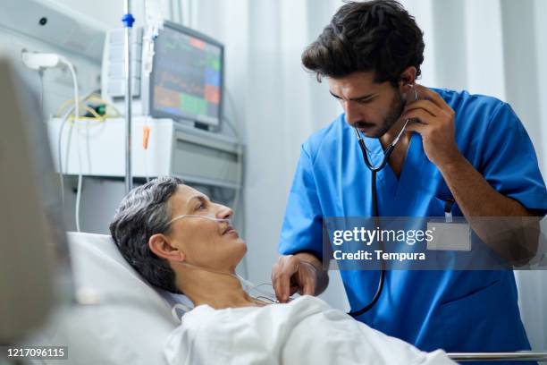 een mannelijke verpleegster luistert met een stethoscoop de borst van een patiënt. - lung doctor patient stockfoto's en -beelden