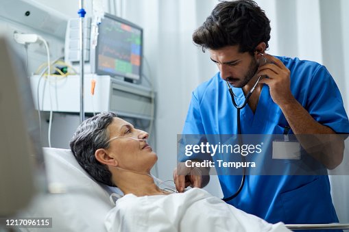 A male nurse is listening with a stethoscope a patient's chest. A male nurse is listening with a stethoscope a patient's chest.