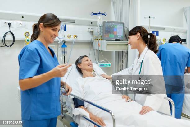 a female doctor comforting a patient lying down on a gurney. - post operation stock pictures, royalty-free photos & images