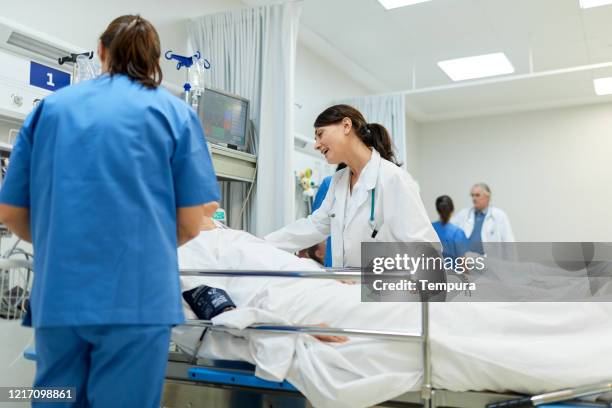 doctors and nurses take care of patients in the post operative area. - post operation stock pictures, royalty-free photos & images