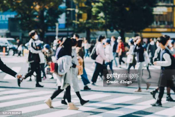 a group of busy commuters commuting in busy downtown city street with protective face mask to protect and prevent from the spread of viruses during covid-19 health crisis - community safety stock-fotos und bilder