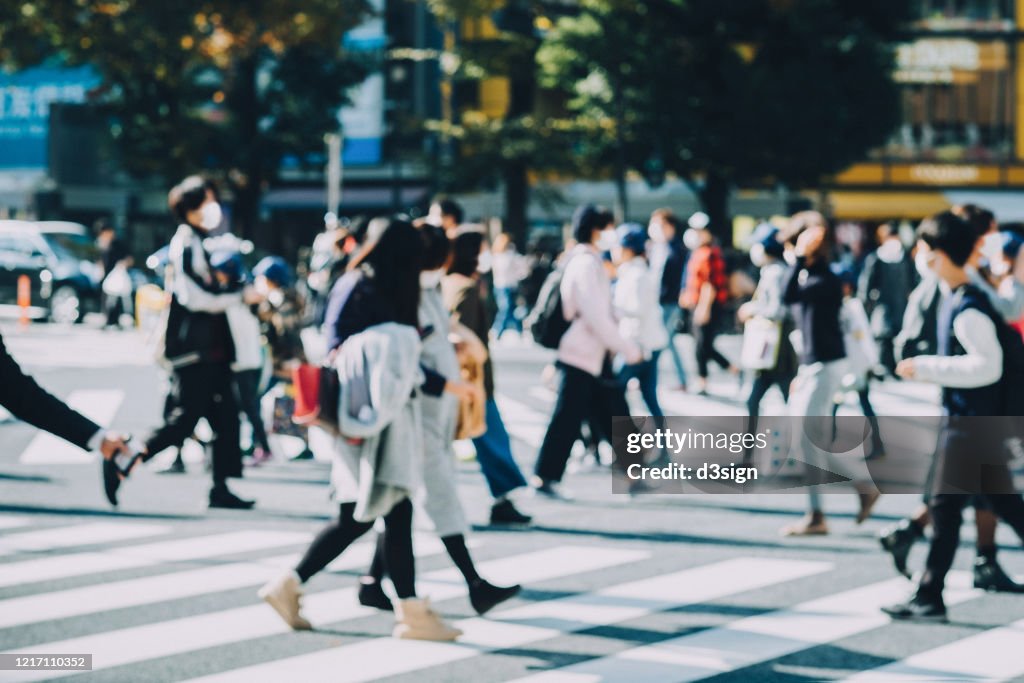A group of busy commuters commuting in busy downtown city street with protective face mask to protect and prevent from the spread of viruses during Covid-19 health crisis