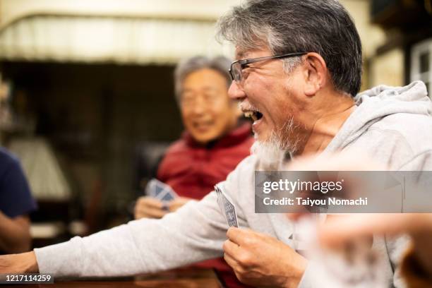 senior man enjoying playing cards with friends - active retirement community stock pictures, royalty-free photos & images