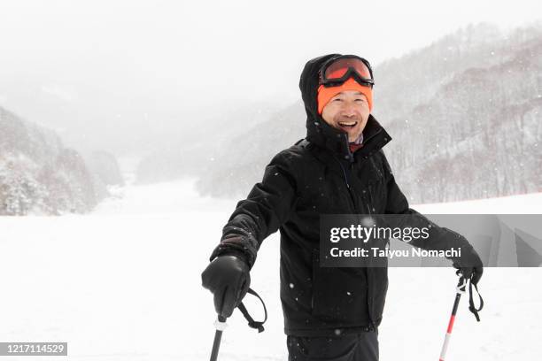 a portrait of a senior man on a ski slope - active seniors winter stock pictures, royalty-free photos & images