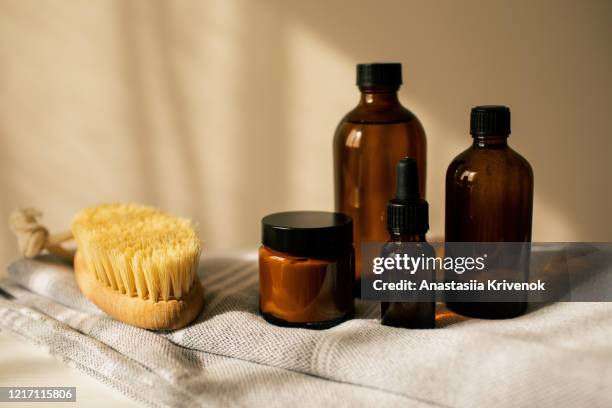 various amber glass bottles for cosmetics, natural skincare and essential oil aromatherapy, or other liquids with anti-cellulite brush on beige background. herbal alternative medicine. copy space. - argan oil stockfoto's en -beelden