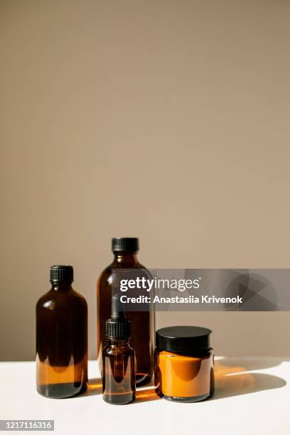 various amber glass bottles for cosmetics, natural skincare and essential oil aromatherapy, or other liquids on beige background. herbal alternative medicine. copy space. - brown hat stock-fotos und bilder