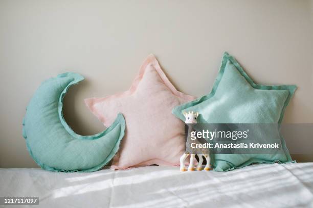 linen blue and pink moon and star pillows toy on light bedding over beige background. decorative baby cushions on nursery. - pink moon stock-fotos und bilder