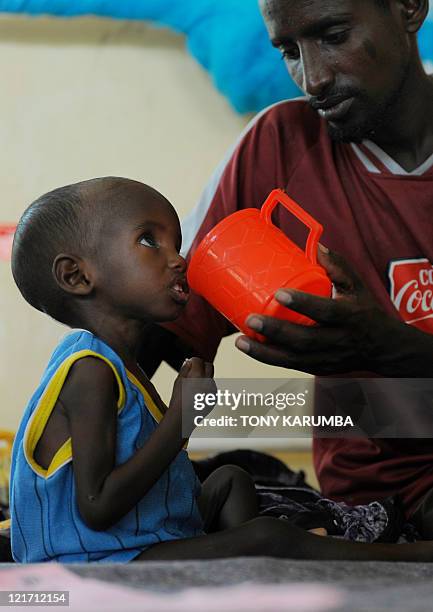 Aden, a three-year-old Somali refugee with his father Abdille, is fed at the stabilisation centre at Hagadere refugee area on August 2, 2011 where he...