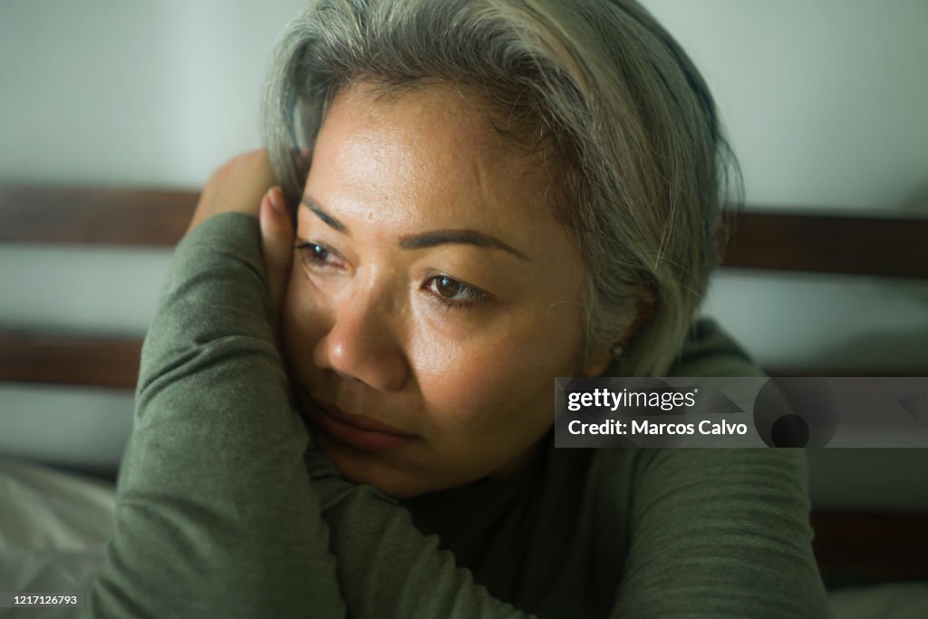 Mature lady crisis - attractive middle aged woman with grey hair sad and depressed in bed feeling scared and lonely thinking worried about covid-19 virus pandemic during home lockdown