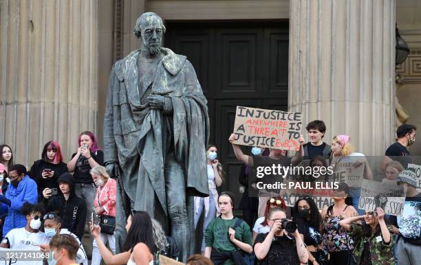 Protesters hold placards next to the statue of 19th century British Prime Minister Benjamin Disraeli outside St George's Hall in Liverpool, northwest...