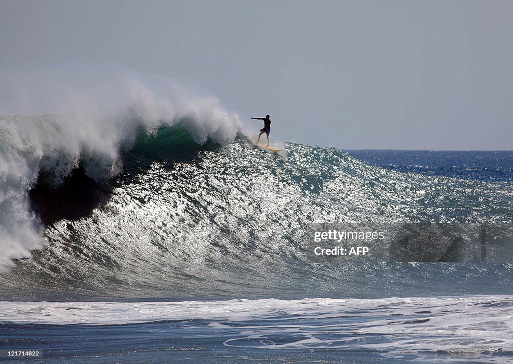 A surfer rides a wave at Le Port beach o
