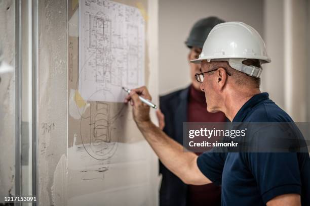 supervisor writing on blueprint - navy blue polo shirt stock pictures, royalty-free photos & images