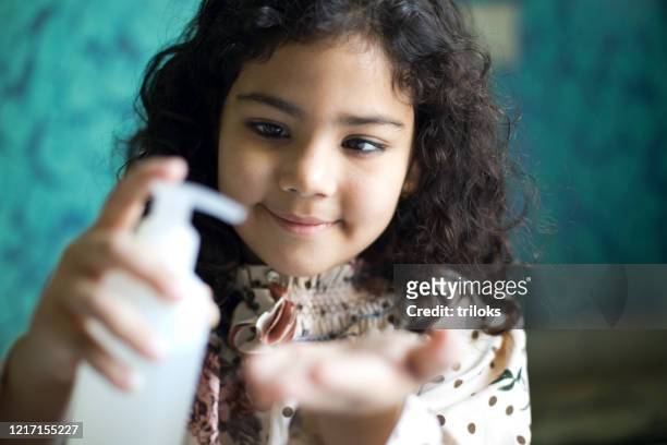 girl pouring sanitizer on palm of hand - respiratory illness stock pictures, royalty-free photos & images