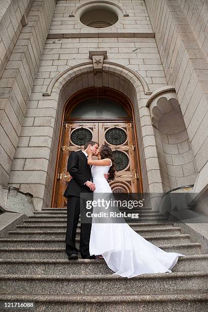 bride and groom kissing in front of church - married church stock pictures, royalty-free photos & images