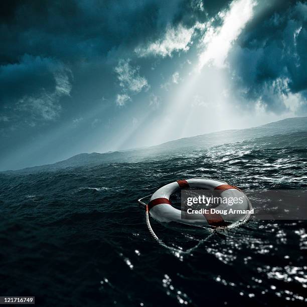 life preserver afloat on stormy seas - cloud save stock pictures, royalty-free photos & images