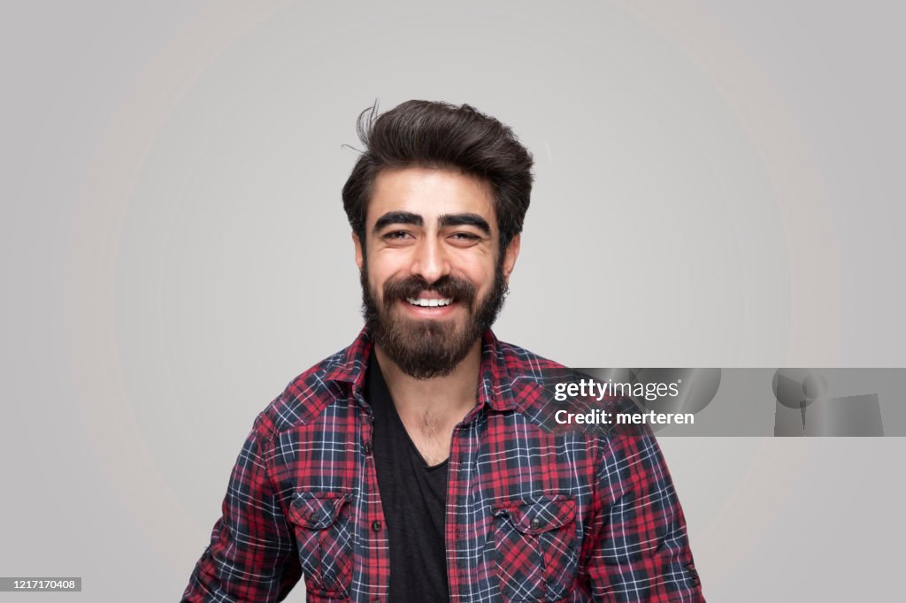 微笑英俊的男人在孤立的灰色背景上看著相機的肖像