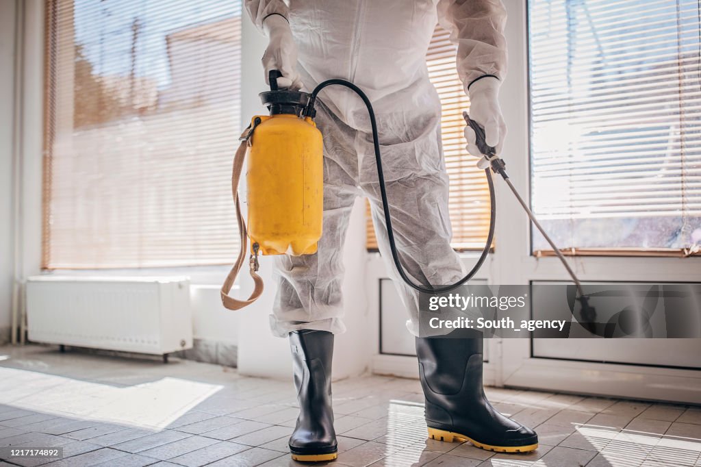 Man in protective suit disinfecting and spraying every room in the building