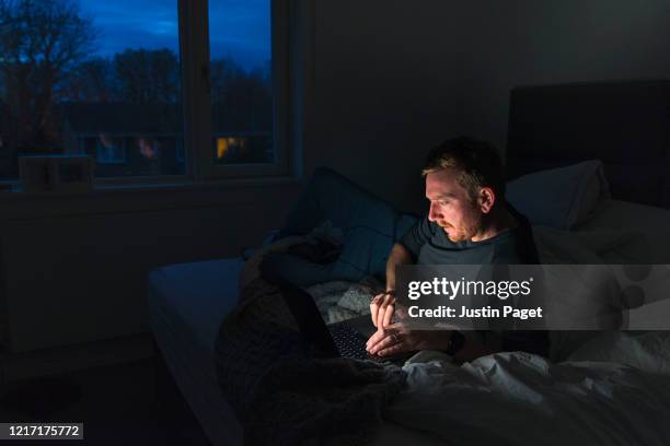 man using laptop in bedroom - wireless technology dark stock pictures, royalty-free photos & images