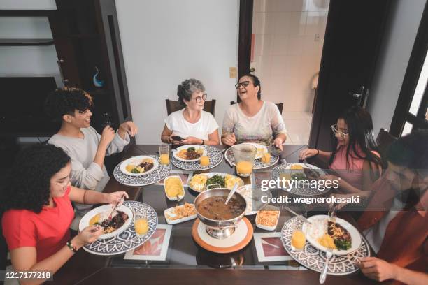 familie die lunch bij eettafel heeft die met feijoada, typische braziliaanse zwarte bonenstoofpot wordt gediend - feijoada stockfoto's en -beelden